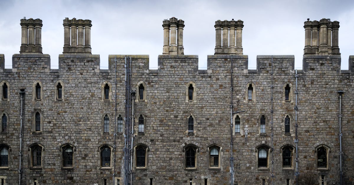 Majestic stone facade of Windsor Castle showcased against a moody sky in England.