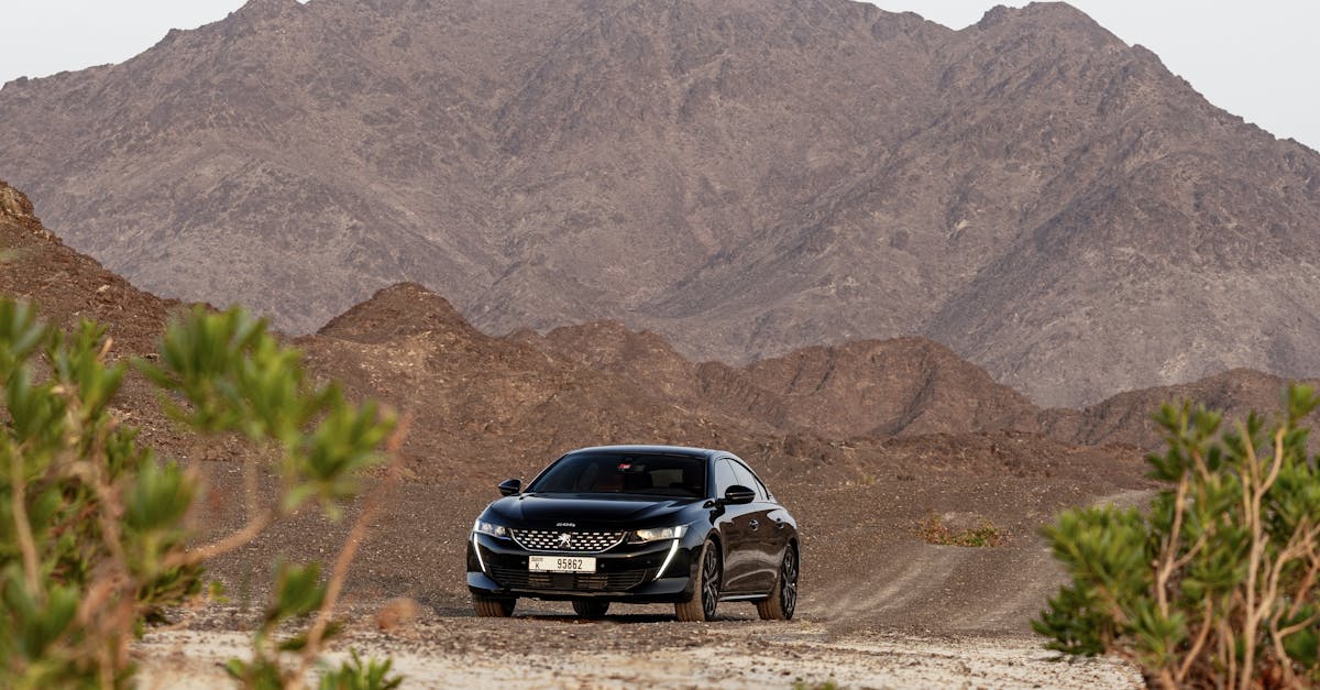 A black car on a dirt road surrounded by scenic mountains in Dubai, perfect for adventure enthusiasts.