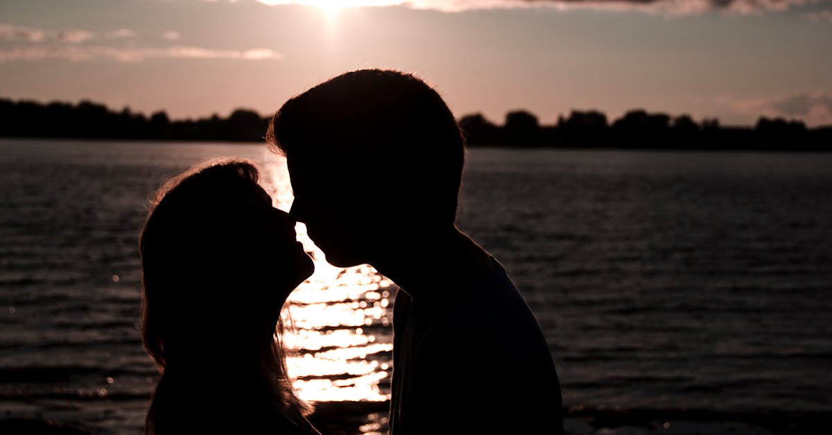 Silhouette of a couple kissing by the lakeside during a breathtaking sunset.