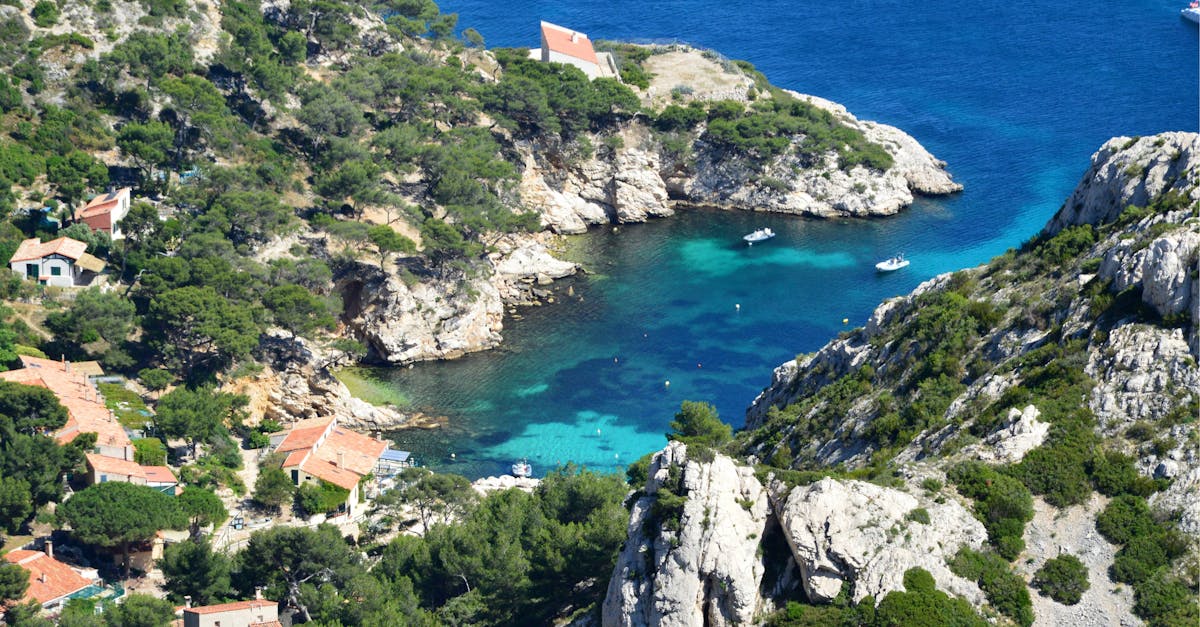 Breathtaking aerial photo of a serene Calanque cove with boats, turquoise water, and lush greenery.