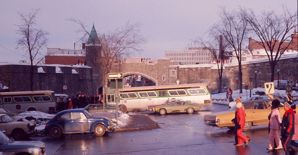 A winter street scene near Porte Saint-Jean in Quebec City, featuring buses, cars, and pedestrians.