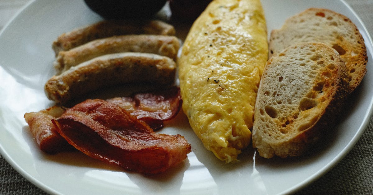 Scrumptious breakfast plate featuring omelette, bacon, sausage, toast on a ceramic plate.
