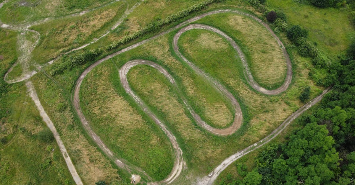 An aerial photograph of a winding dirt track in a lush green field in Hauts-de-France, France.