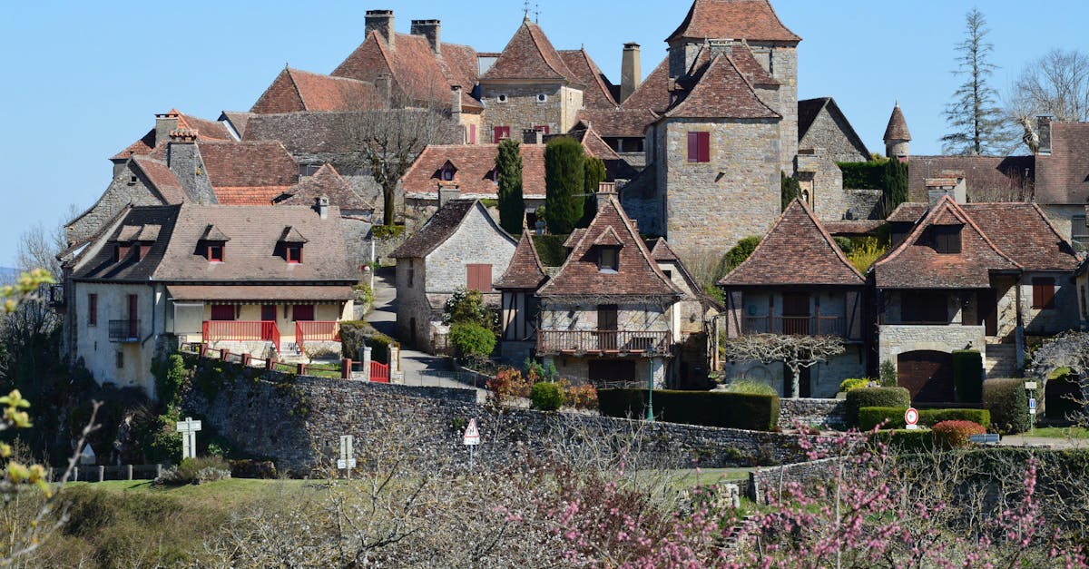 View of a picturesque French village with classic stone houses and red roofs under a clear sky.
