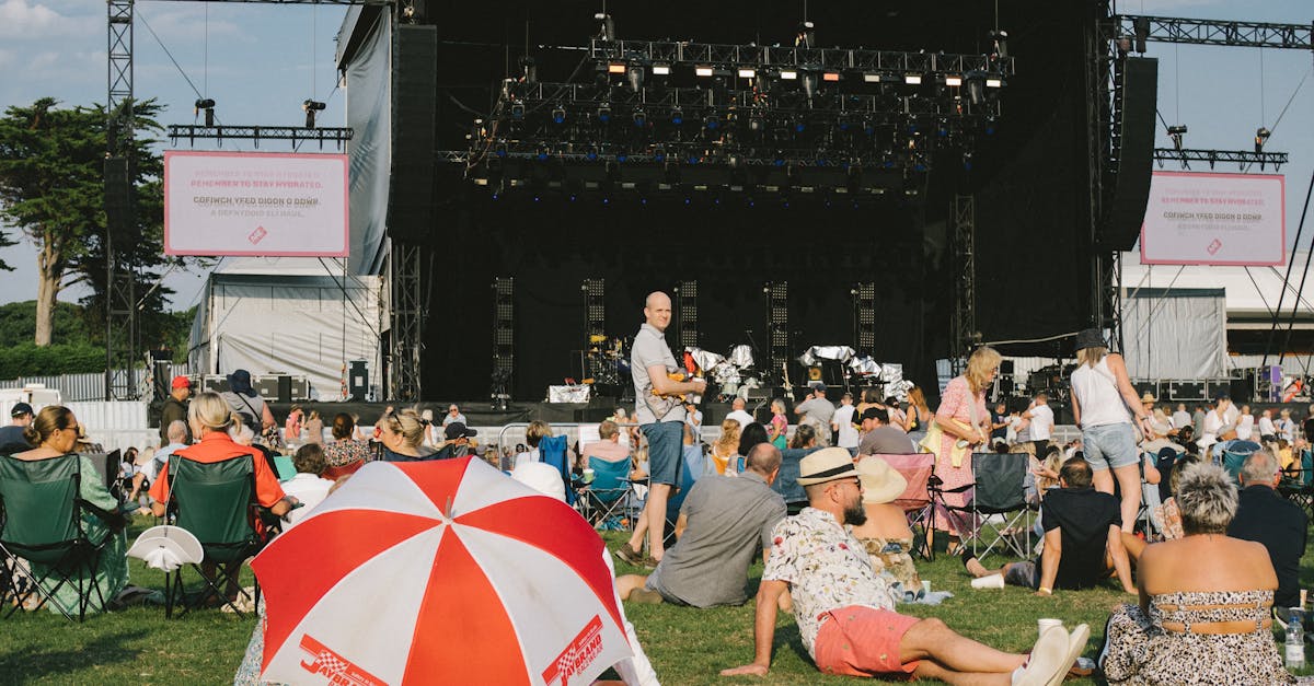A vibrant outdoor music festival with a crowd enjoying the event, seated and relaxed.
