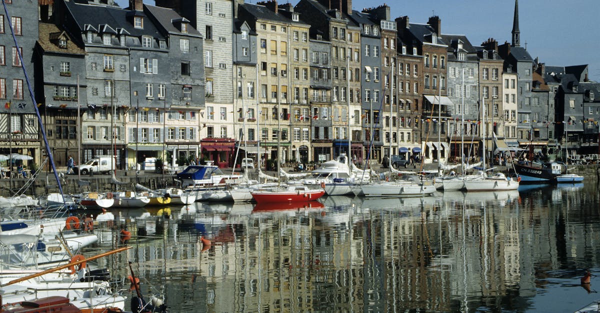 Charming boats docked by colorful historic buildings in Honfleur's Vieux Bassin, Normandy, France.