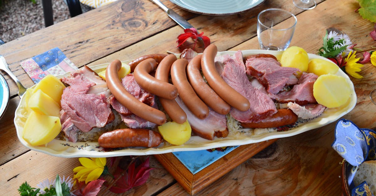 A beautifully arranged platter featuring sausages, meats, and potatoes on a rustic wooden table.
