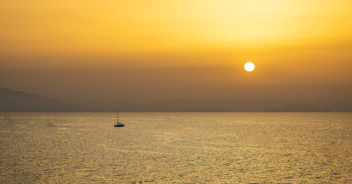 A peaceful ocean sunset with a lone sailing boat under a golden sky, epitomizing serenity.