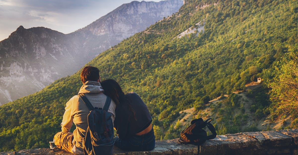 Couple sitting together enjoying a scenic mountain view at sunset, embodying love and adventure.