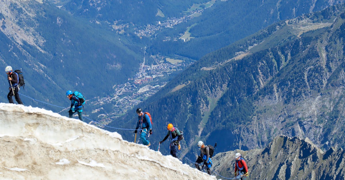 Adventurers climbing a snowy ridge with stunning views of Chamonix in the background.
