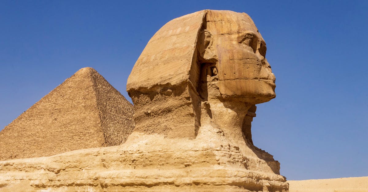 Majestic view of the Great Sphinx and Pyramid against a clear blue sky in Giza, Egypt.