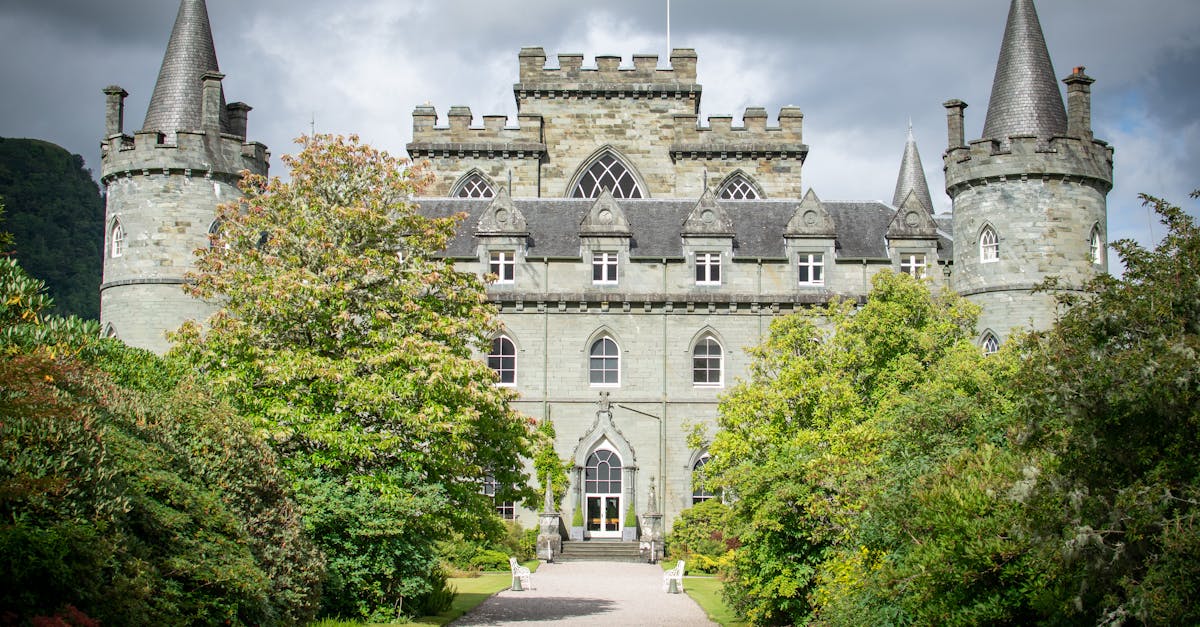 Stunning view of Inveraray Castle showcasing its grand architecture surrounded by lush gardens under a dramatic sky.