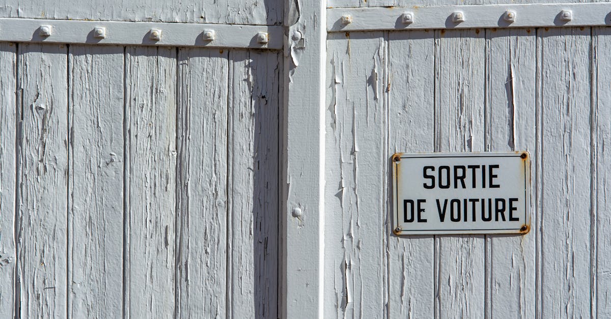 Close-up photo of a weathered wooden wall with a French 'car exit' sign.