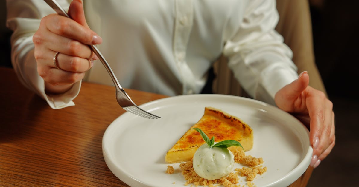 A woman in a white shirt eating pie with vanilla ice cream and mint.