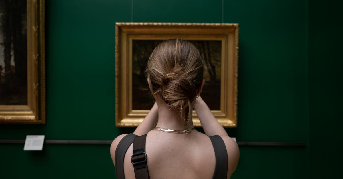 Back view of a woman photographing a painting in an art gallery.