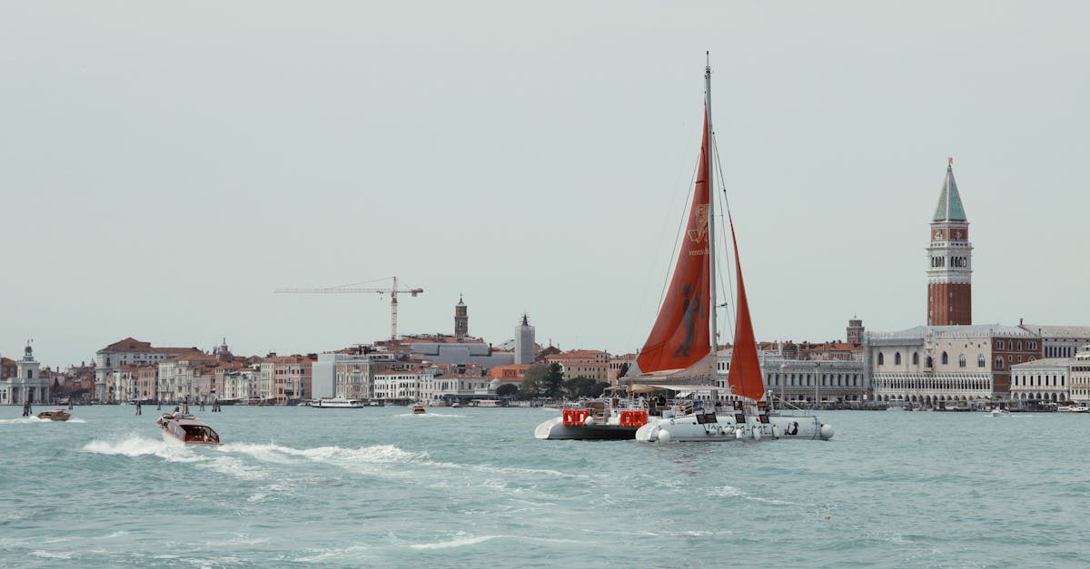 Sailboats cruising past Venice's iconic landmarks on a tranquil day in Italy.