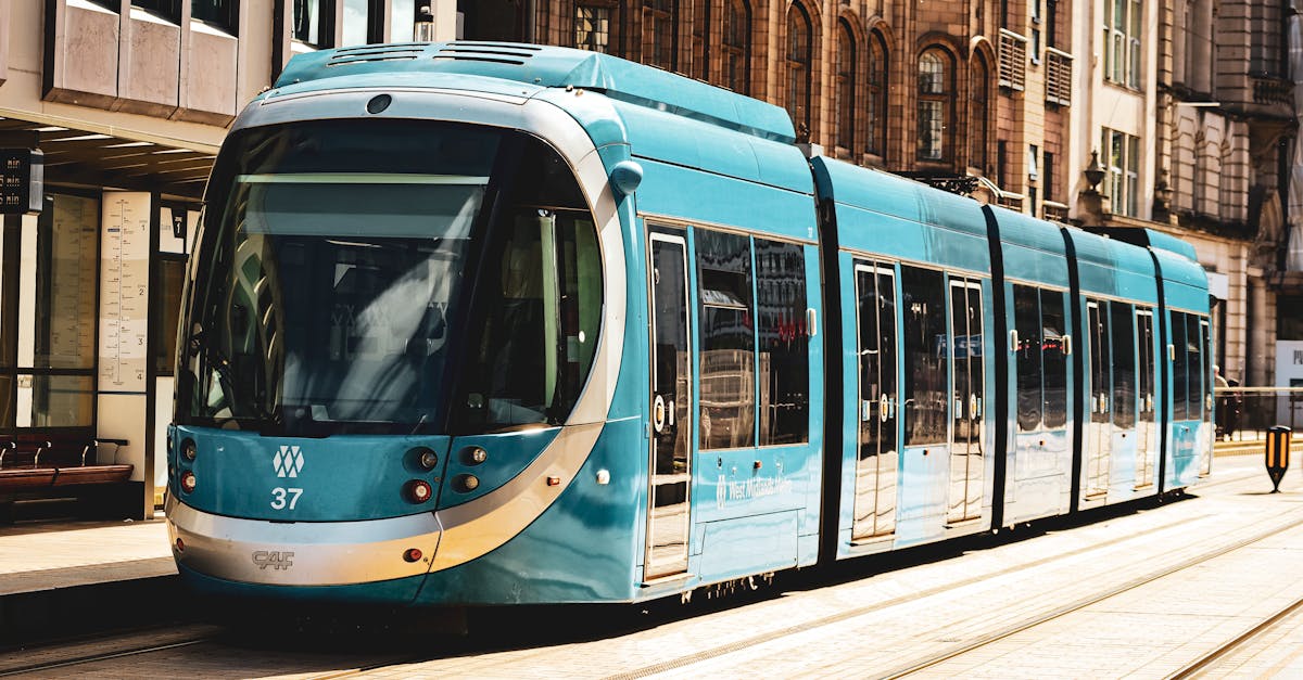 A vibrant blue tram on the streets of Birmingham, UK, showcasing urban transit.