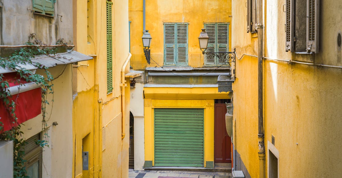 Picturesque alley in Nice, France with vibrant yellow buildings and classic shutters.