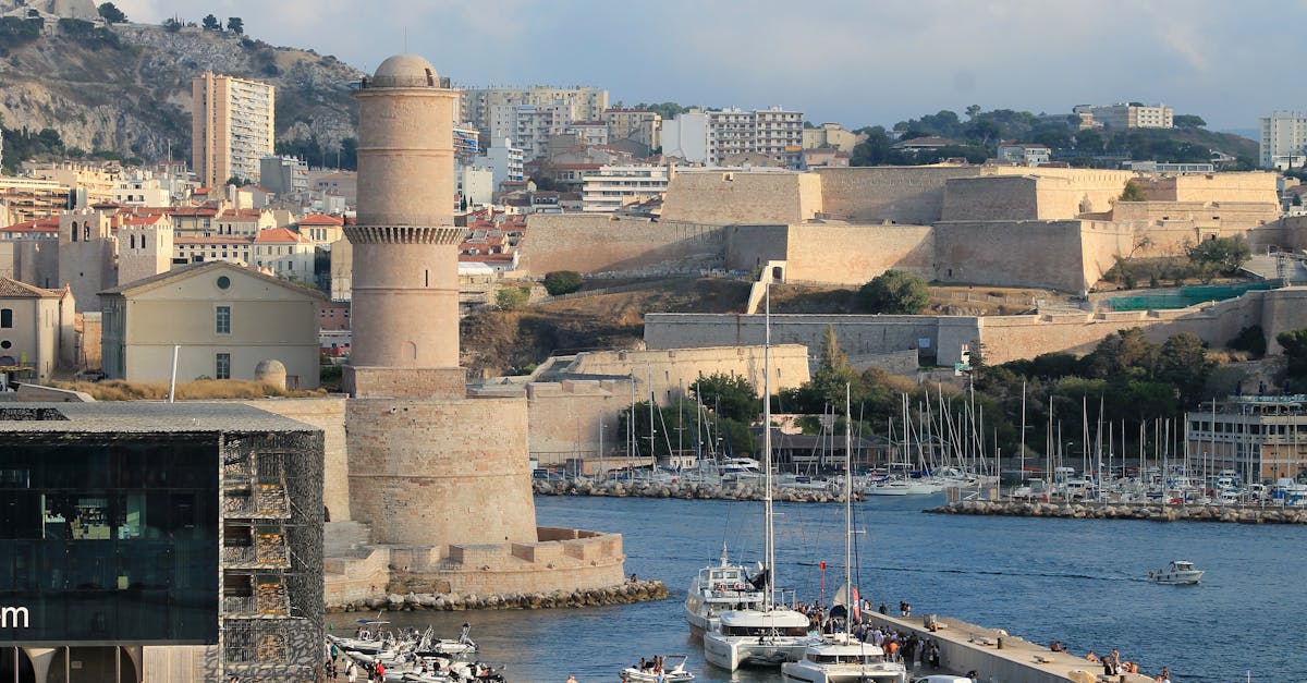 Scenic view of Marseille's historic Fort Saint-Jean and vibrant harbor in France, capturing urban architecture and waterfront activity.