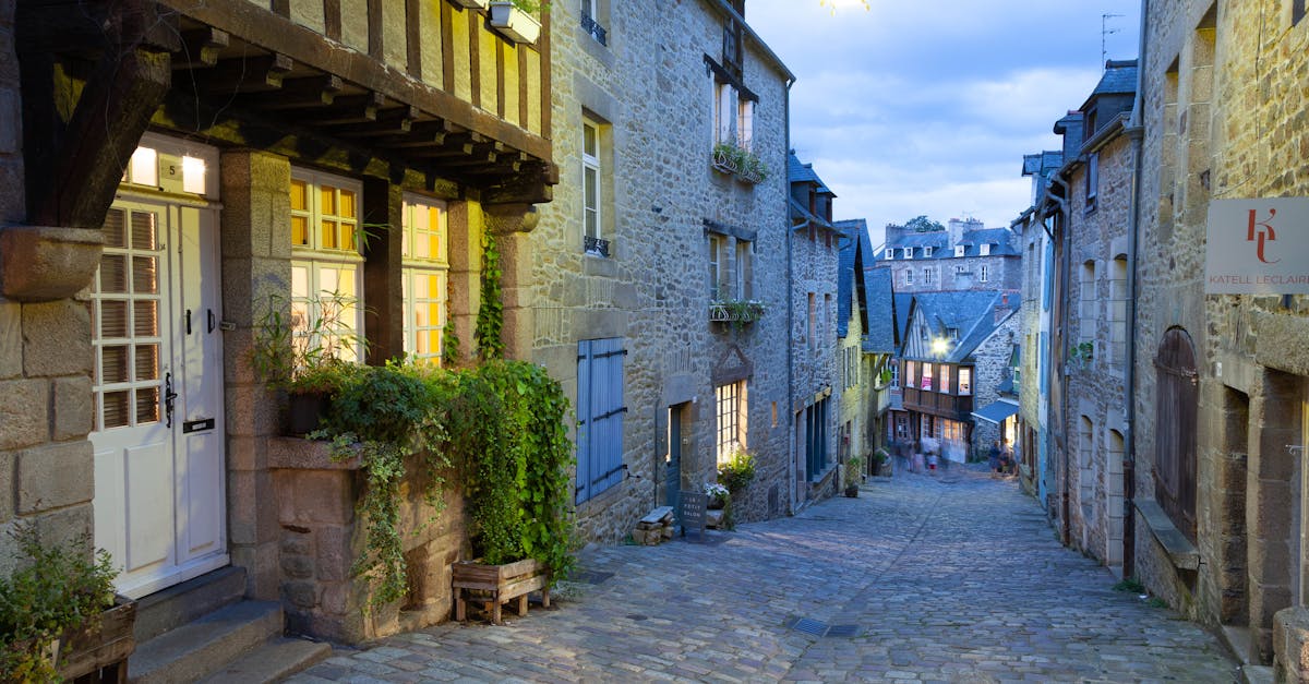 Explore the illuminated cobblestone streets of historic Dinan, Brittany at dusk.