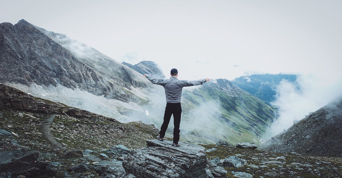A man stands on a mountain peak with arms outstretched, embracing freedom.