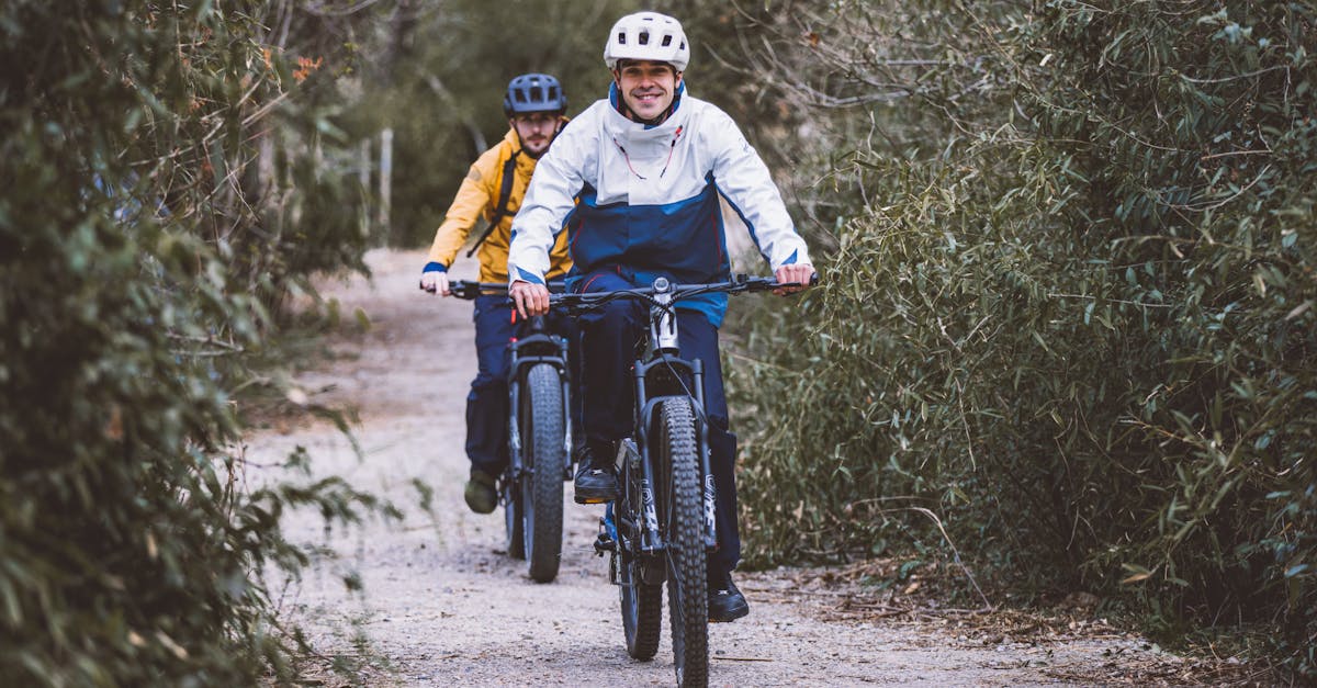 Two men ride bicycles along a forest path, enjoying a day of recreation outdoors.