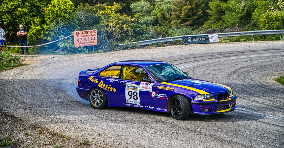 Dynamic shot of a blue sports car drifting around a curve on a race track surrounded by greenery.