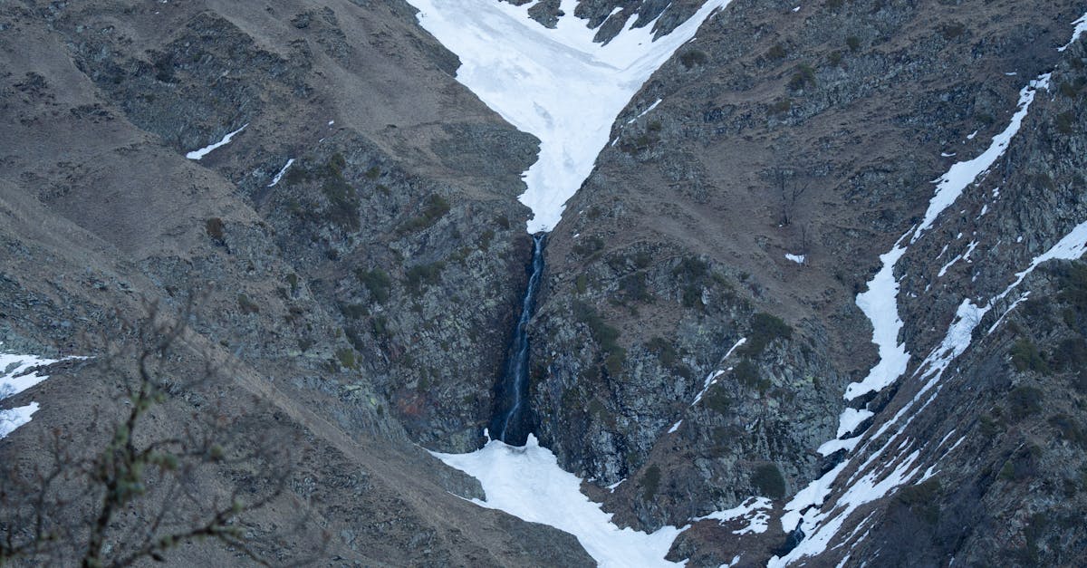 Stunning view of a snow-capped mountain valley with a hidden waterfall.
