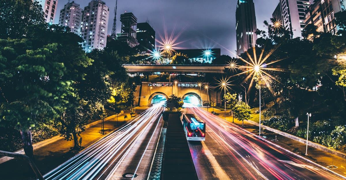 Captivating long exposure shot of a city highway at night, showcasing vibrant light trails and towering buildings.