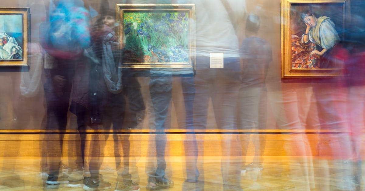 Blurred motion of gallery visitors observing art paintings in a bright, colorful space.