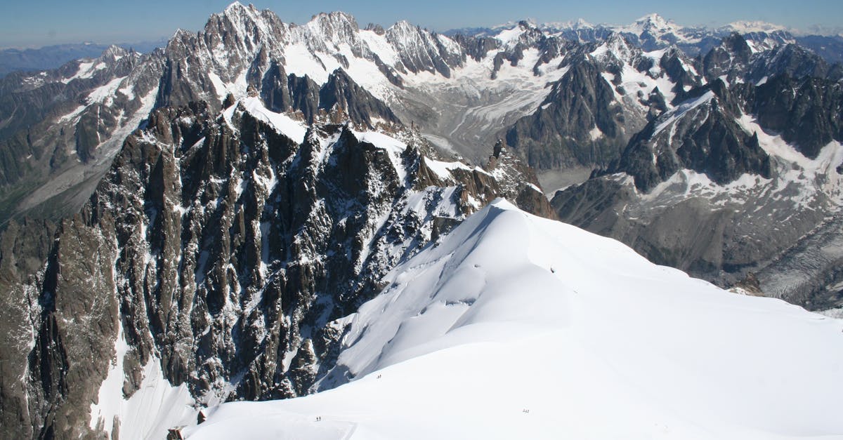 Explore the stunning snowy peaks and ridges of a majestic alpine mountain range bathed in sunlight.