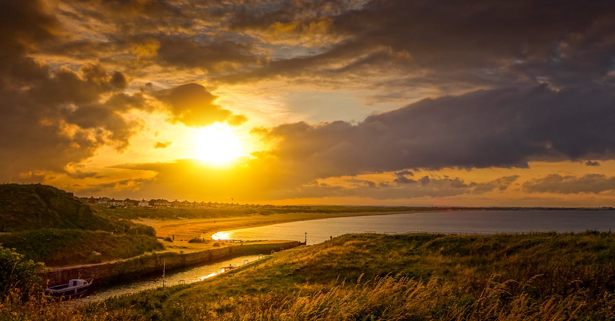 Stunning sunset over a serene coastal landscape with dramatic clouds and calm sea.