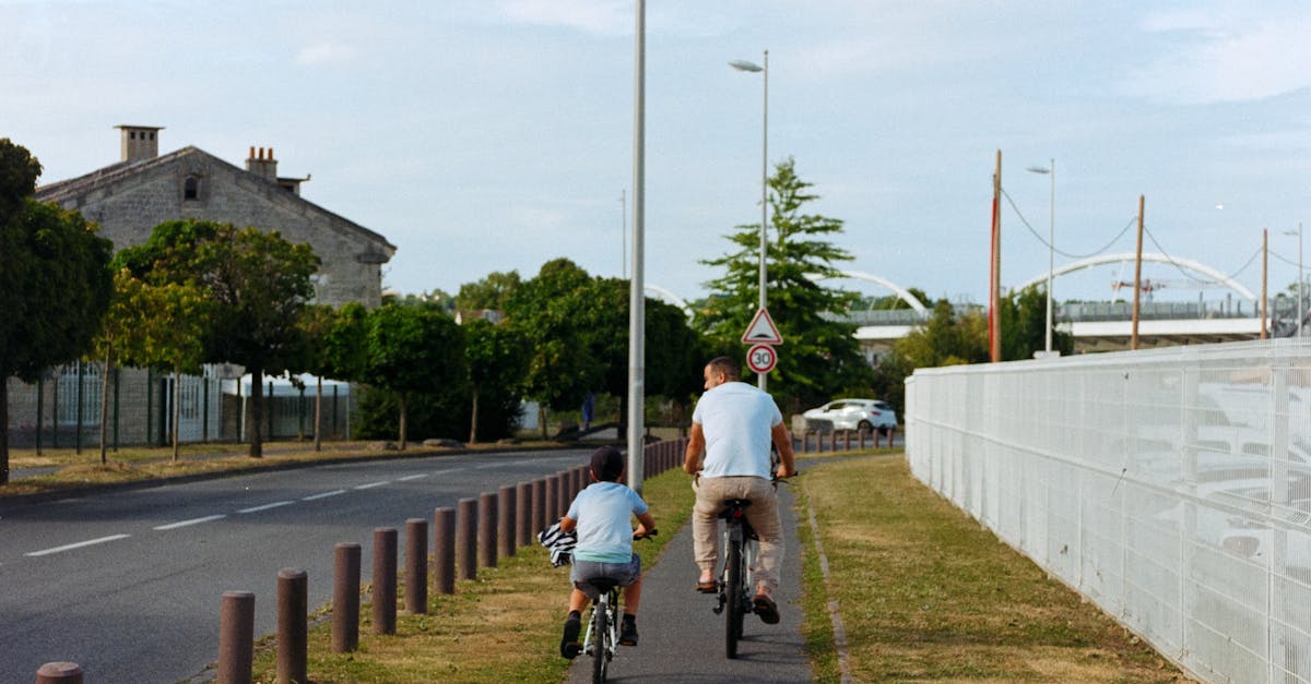 A father and son enjoy cycling on an urban path in a serene summer setting.
