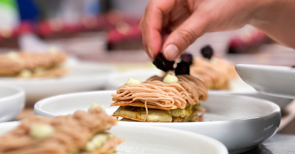 A chef's hand placing garnish on an elegant chestnut dessert in a restaurant.