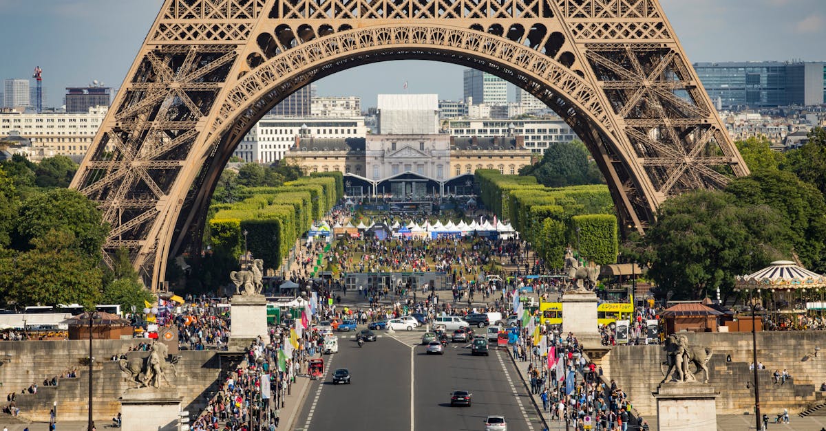 Eiffel Tower framing a bustling street scene in Paris with vibrant activity and landmarks.
