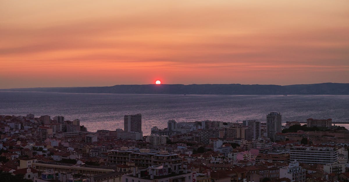 Beautiful cityscape of a coastal city during a vibrant sunset, with the ocean horizon.