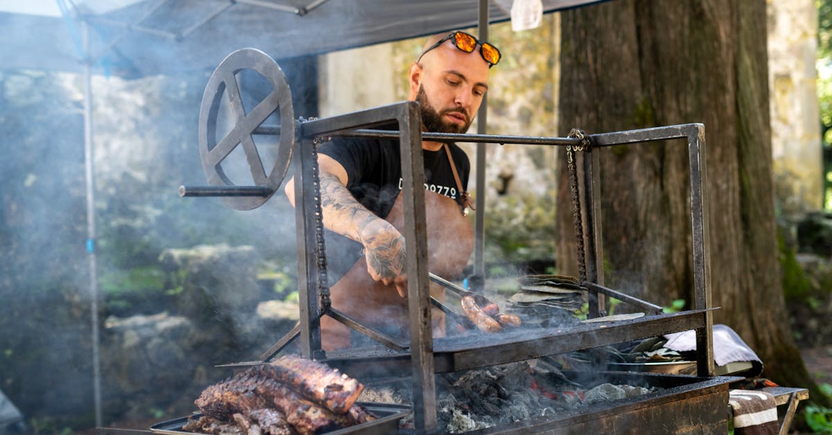 Chef grilling ribs and sausages at an outdoor barbecue event with smoke.