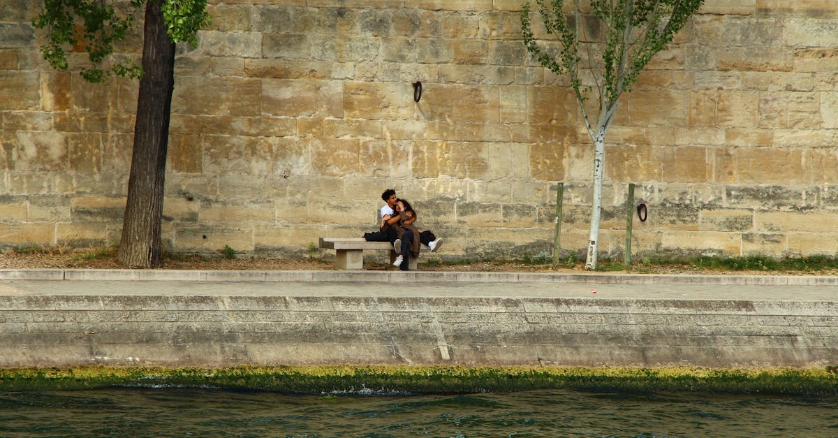 A couple embraces on a bench alongside the Seine River in Paris.