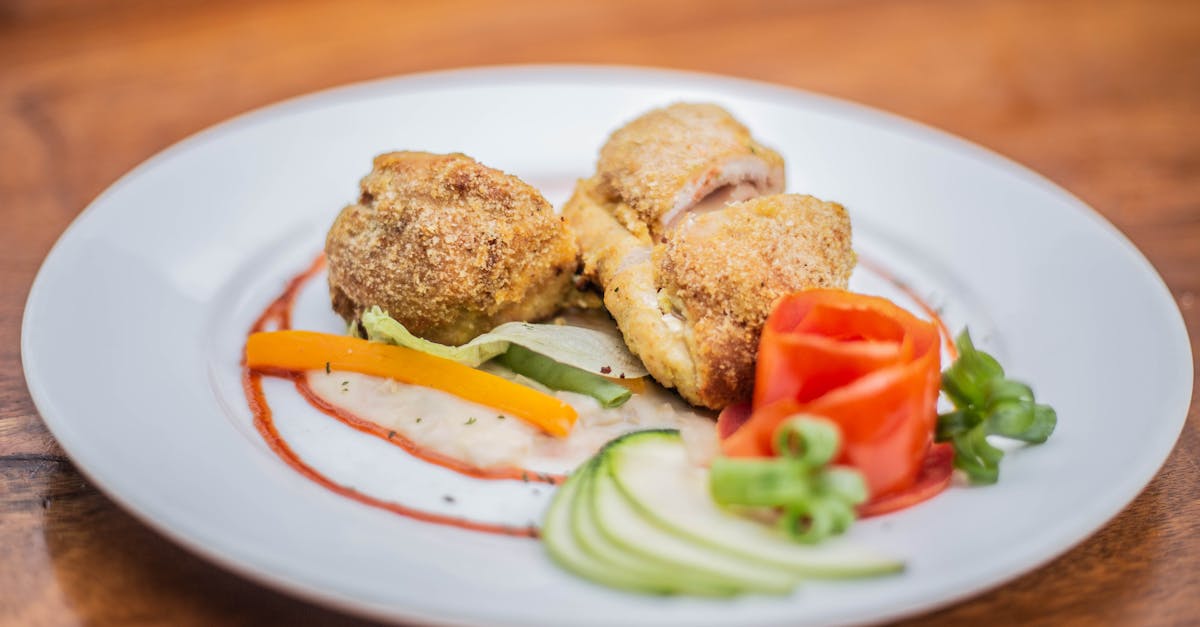 A beautifully plated breaded chicken dish with vibrant vegetables on a modern white plate.