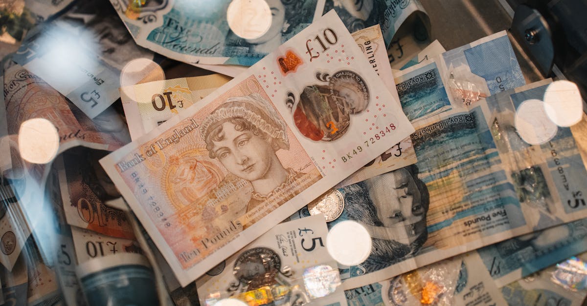 A detailed view of British £5 and £10 pound sterling notes with coins, featuring warm bokeh effects.