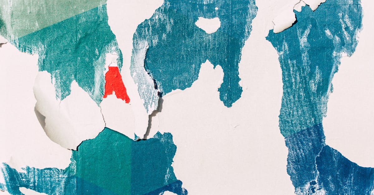 A close-up of a textured wall with layers of colorful peeling paint, creating an abstract pattern.