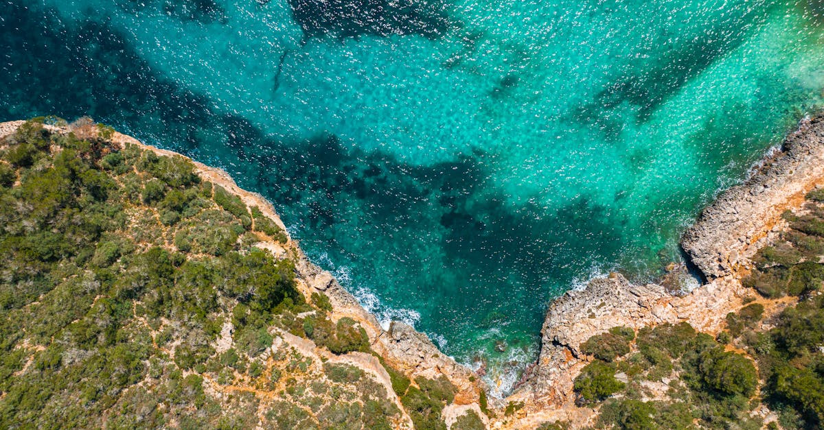 Stunning aerial view of rocky cliffs and clear turquoise sea in Mallorca, perfect for travel inspiration.