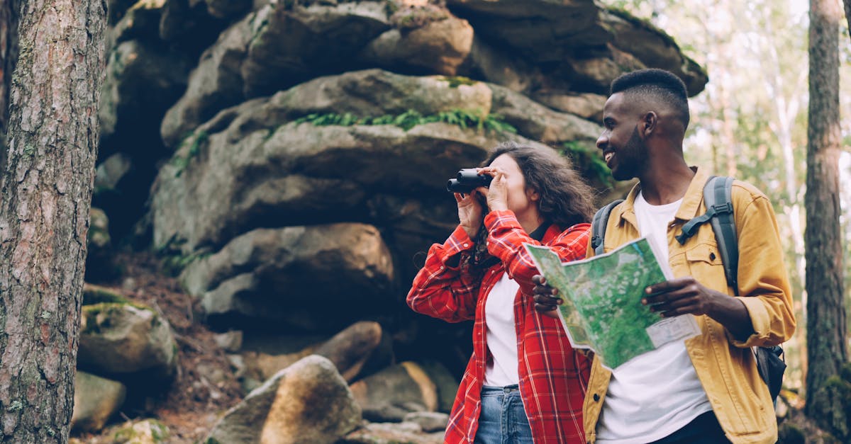 Two hikers exploring a forest with a map and binoculars, enjoying an outdoor adventure.