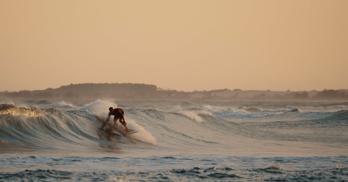 A surfer skillfully rides a wave at sunset, showcasing agility and balance against a picturesque coastal backdrop.