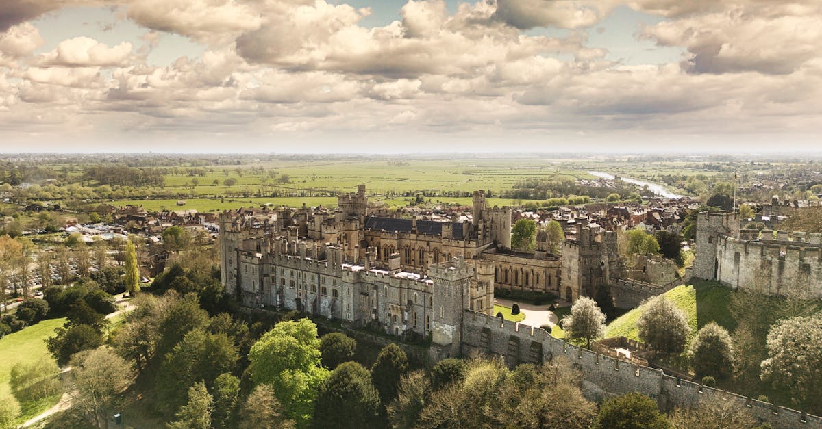 A breathtaking aerial shot of Arundel Castle surrounded by lush greenery and under a dramatic sky.