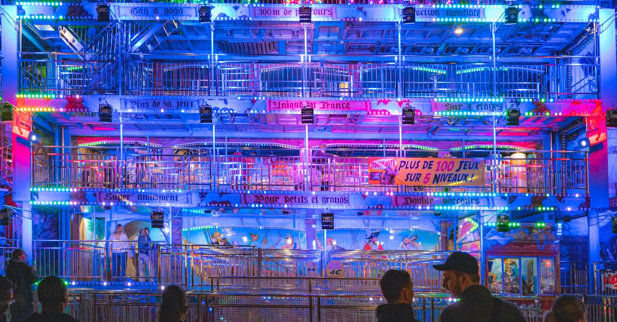 Colorful illuminated fairground attraction at night in Caen, France with people enjoying the lively atmosphere.