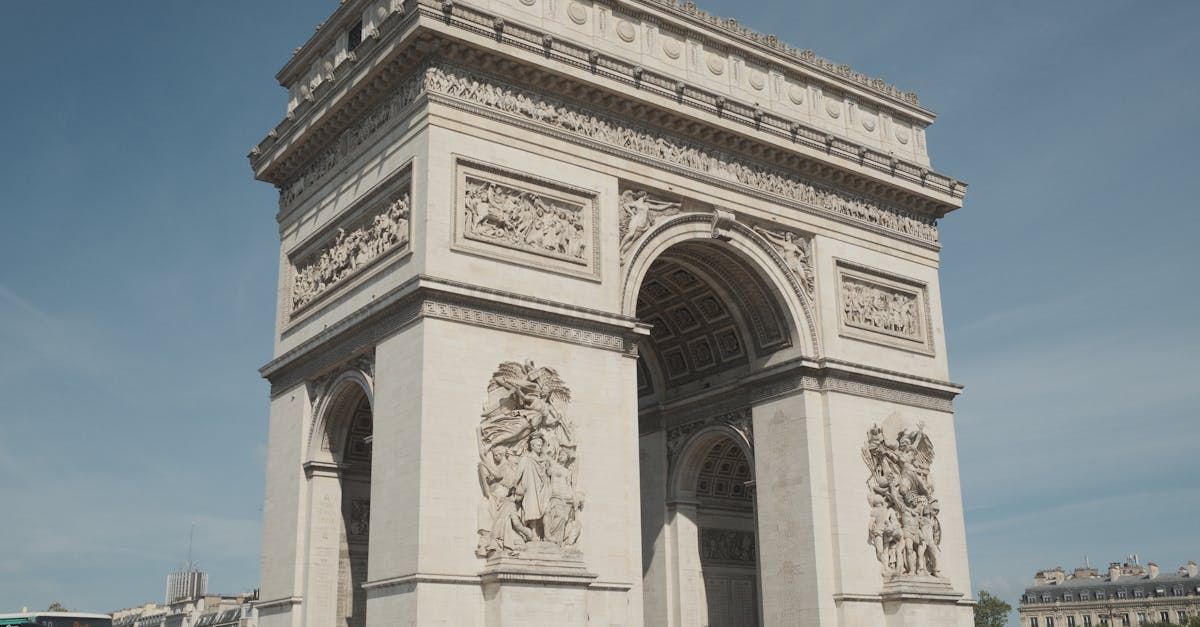 Beautiful shot of the Arc de Triomphe, capturing its stunning architecture under a bright blue sky in Paris.