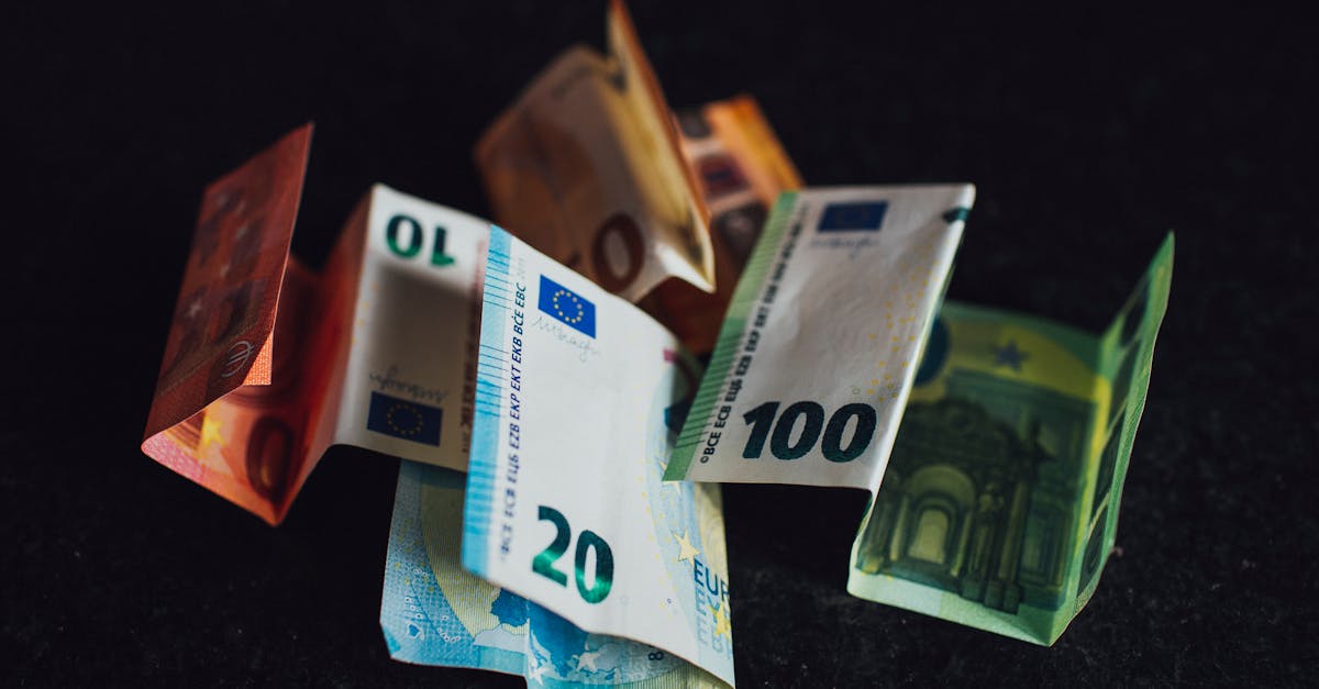 Assorted Euro banknotes in denominations of 10, 20, and 100 on a dark surface, highlighting European currency.