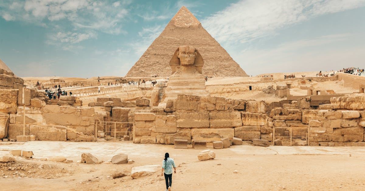 Back view of unrecognizable man walking towards ancient monument Great Sphinx of Giza