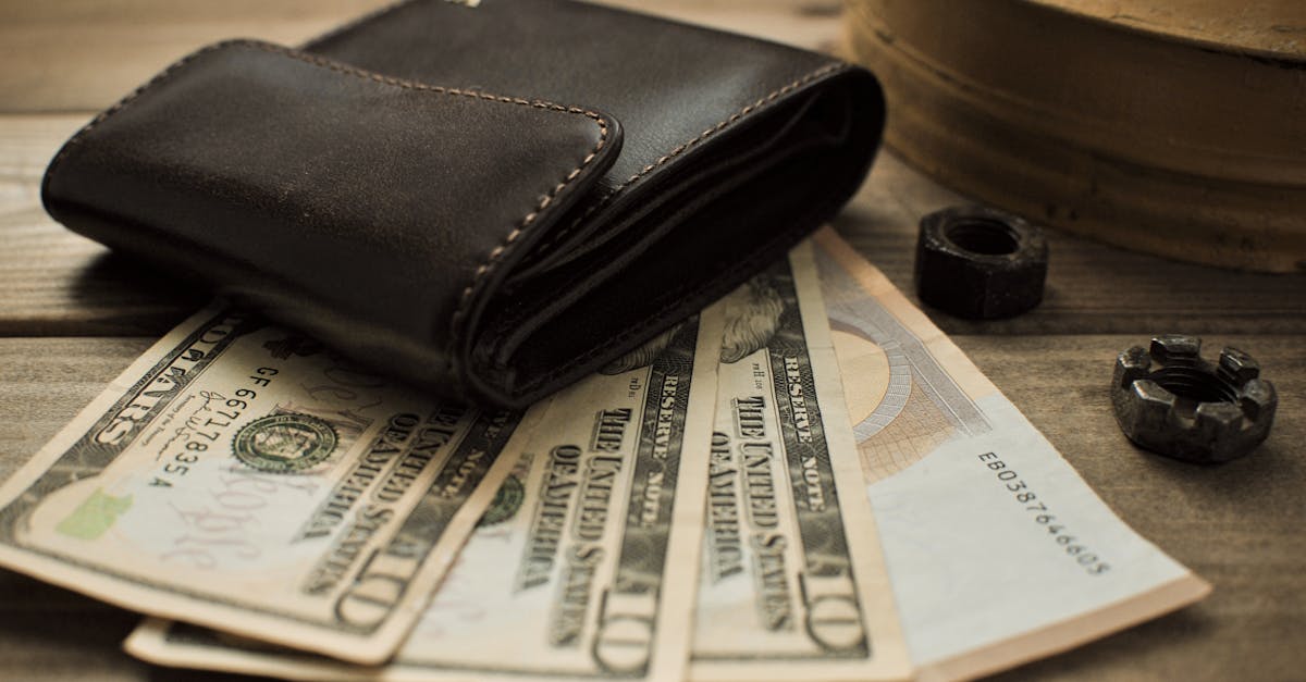Close-up view of a leather wallet with US dollar bills on a wooden table.